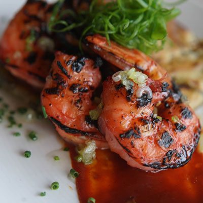 close-up of charred red shrimp topped with greens