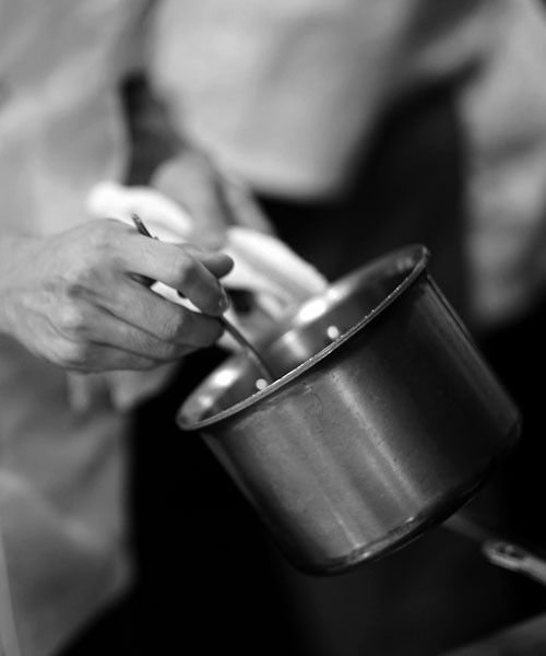 close-up of chef stirring something in a silver pot